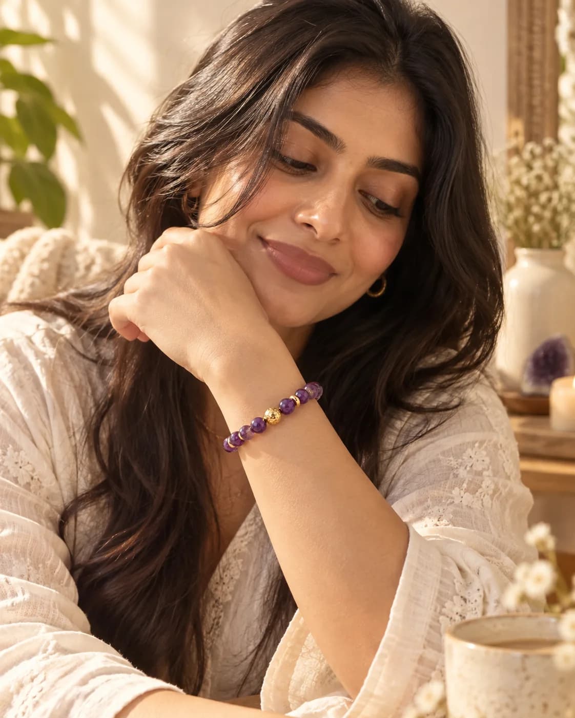 Woman resting her chin on her hand, wearing an amethyst beaded bracelet in warm afternoon light